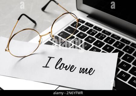 Papier mit handgeschriebener Phrase Ich liebe mich und Brille auf Laptop, Nahaufnahme Stockfoto