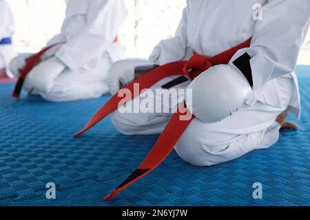 Kinder in Kimonos, die auf dem Trainingsgelände sitzen, Nahaufnahme Stockfoto