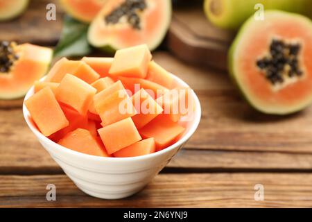 Frische gewürfelte Papaya-Früchte in Schüssel auf Holztisch, Nahaufnahme. Platz für Text Stockfoto