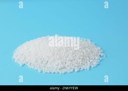 Ammoniumnitrat-Pellets auf hellblauem Hintergrund, Platz für Text. Mineraldünger Stockfoto