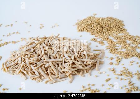 Ungekochte hausgemachte Eiernudeln und grobe Bulgur-Weizenkörner, isoliert auf weißem Hintergrund. Stockfoto