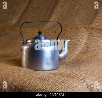 Eine alte Soldatenteekanne aus Aluminium aus dem Zweiten Weltkrieg vor dem Hintergrund von Leinenholz. Stockfoto