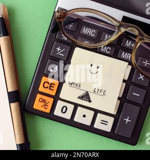 Work-Life-Balance – Konzept für einen abgeschlossenen Arbeitstag: Stift, Brille, Taschenrechner und handgezeichneter Papieraufkleber Stockfoto