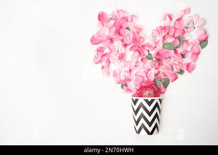 Das Konzept eines Blumenladens und Coffeeshops. Eine Kaffeetasse und Blumen. Kaffee zum Mitnehmen. Blütenblätter, Rosen und Ranunculus. Valentinstag Stockfoto