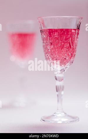 Ein Paar hält zwei rosafarbene Cocktails zum Valentinstag. Liebes- und Jubiläumsatmosphäre mit Herzen. Romantisches Konzept Stockfoto