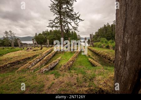 Das Langhaus in Haida mit Gedenkmasten und Bestattungsmasten blickt auf Kunghit Island, Haida Gwaii, BC. Stockfoto