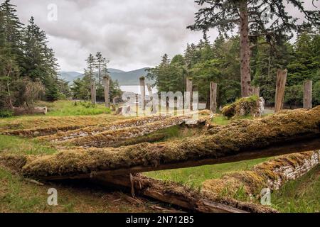 Überreste eines Langhauses in Haida mit stehenden Gedenkmasten und Bestattungsmasten, S'Gaang Gwaii, Haida Gwaii, BC Stockfoto