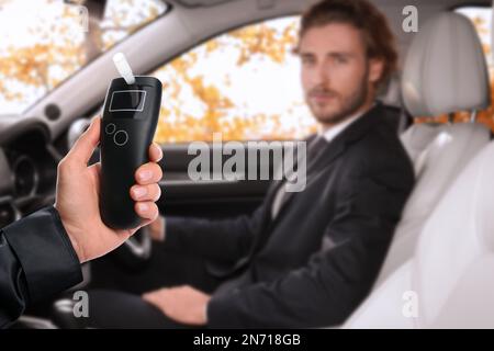 Polizist mit Atemgerät und Mann im Auto. Alkoholkonsum während der Fahrt Stockfoto