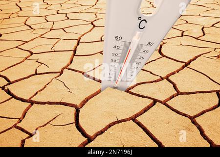 Thermometer mit Temperaturanzeige in gerissener Erde, Hitze, Dürre, Trockenheit Stockfoto