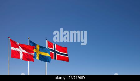 Dänische, schwedische und norwegische Nationalflaggen, die im Wind vor blauem Himmel winken Stockfoto