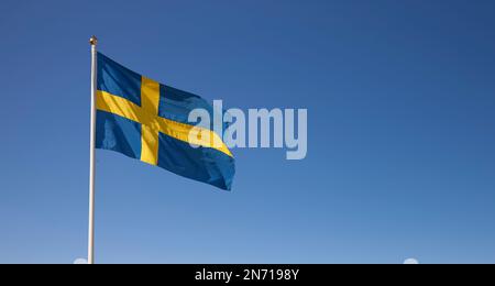 Die schwedische Nationalflagge winkt im Wind gegen den blauen Himmel Stockfoto