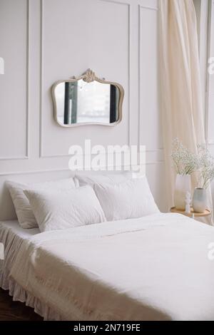 Spiegel, der an einer Wand über einem Bett im Schlafzimmer hängt Stockfoto