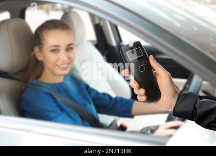 Polizist mit Atemgerät und Frau im Auto. Alkoholkonsum während der Fahrt Stockfoto