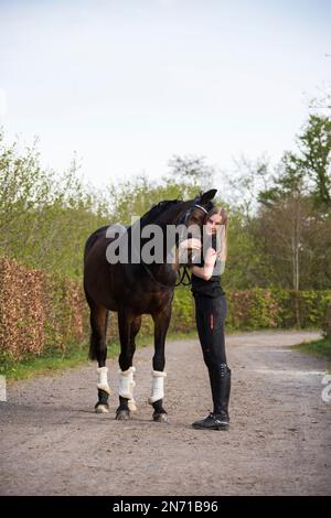 Teenager, die den Kopf ihres braunen Pferdes umarmt Stockfoto