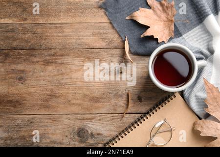 Flache Liegezusammensetzung mit einer Tasse Tee und Herbstblättern auf einem Holztisch. Platz für Text Stockfoto