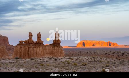 Mondaufgang über den Three Sisters Hoodoos in der Abenddämmerung, Goblin Valley State Park, Utah, USA Stockfoto