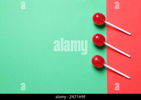 Drei rote Lutscher auf farbigem Hintergrund, flach liegend. Platz für Text Stockfoto