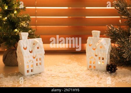 Wunderschöne hausförmige Weihnachtslaternen mit brennenden Kerzen auf der Fensterbank Stockfoto