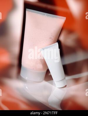 Gruppe von Kosmetikröhren und -Gläsern für Eigenmarken in reflektierenden Konzeptstudiofotos. Insgesamt ist diese Farbe Rot - Rosa. Stockfoto
