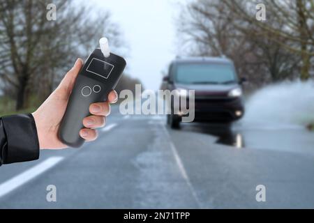 Polizeibeamter mit Atemgerät und Auto auf der Straße. Alkoholkonsum während der Fahrt Stockfoto