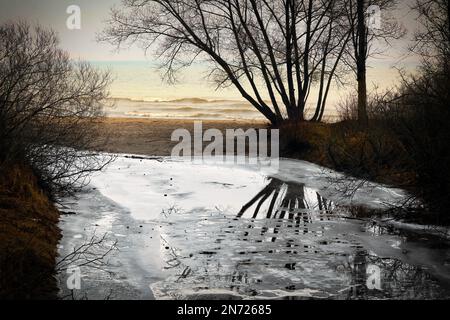 Am Silver Creek bildet sich Eis, und das Wasser spiegelt sich wieder. Dort fließt es zum Lake Michigan in Manitowoc, Wisconsin. Stockfoto