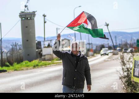 Nablus, Palästina. 10. Februar 2023. Ein Palästinenser hisst während der Demonstration vor israelischen Soldaten eine palästinensische Flagge. Die israelische Armee schloss den Hawara-Kontrollpunkt südlich von Nablus, was zu Protesten gegen die Schließung führte. (Foto von Nasser Ishtayeh/SOPA Images/Sipa USA) Guthaben: SIPA USA/Alamy Live News Stockfoto