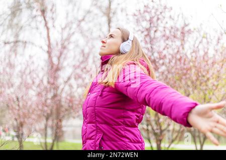 Entspannte Frau mit Kopfhörern, die frische Luft atmet und im Park Musik hört Stockfoto