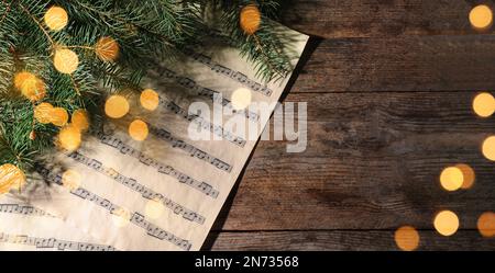 Weihnachtsgrußkartendesign. Notenblätter und Tannenbaum auf Holzhintergrund, Draufsicht mit Platz für Text Stockfoto