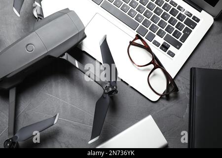 Moderne Drohne mit Videokamera und Laptop auf grauem Steintisch, flach liegend Stockfoto