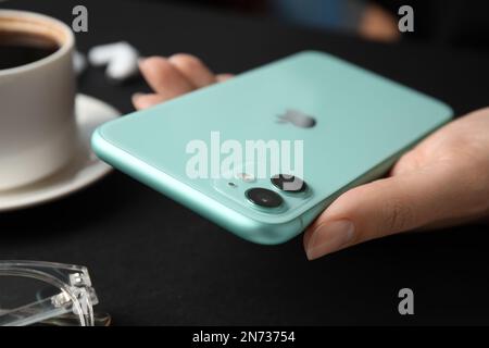 MYKOLAIV, UKRAINE - 9. JULI 2020: Frau mit iPhone 11 Green am Tisch, Nahaufnahme Stockfoto