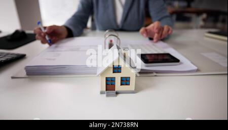 Person Hand Tun Immobilien Steuerberechnung Mit Rechner Des Hauses Modell Stockfoto