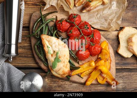 Köstliches gekochtes Huhn und Gemüse auf Holztisch, flach liegend. Gesunde Mahlzeiten aus der Airfryer Stockfoto