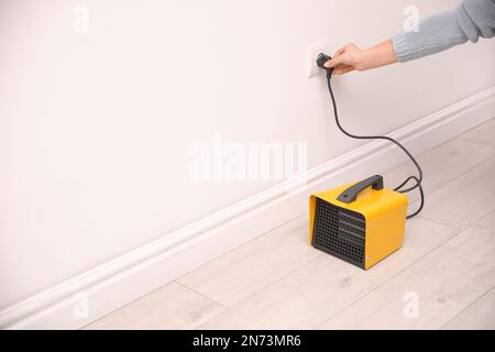 Frauen schließen moderne elektrische Heizlüfter in Innenräumen an, schließen zusammen. Platz für Text Stockfoto