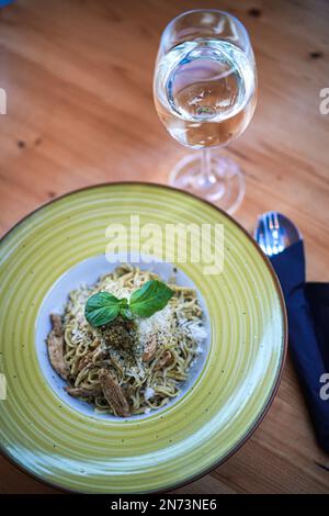 Ein eleganter Spaghetti Carbonara-Teller mit einem Glas Weißwein. Stockfoto