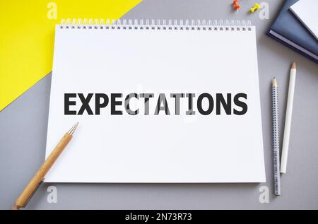 Erwartungen. In Noebook geschriebener Text auf gelbem grauen Hintergrund. Geschäftskonzept. Draufsicht, flach liegend Stockfoto