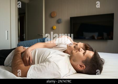 Schöne Frau in lässiger Kleidung liegt auf der Schulter ihres Mannes Stockfoto