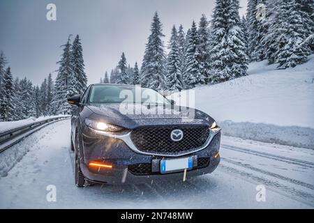 Italien, Veneto, Belluno, Mazda Motor Corp CX-30 Crossover Sport Utility Vehicle (SUV) auf einer Bergstraße im Winter während eines Schneefalls, Dolomiten Stockfoto