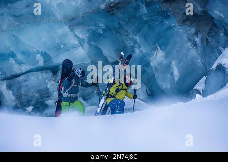 Zwei professionelle Snowboarder und Skifahrer erkunden und fahren eine Gletscherspalte/Eishöhle hoch oben auf dem Pitztal-Gletscher, Pitztal, Tirol, Österreich Stockfoto