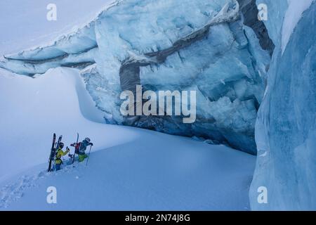 Zwei professionelle Snowboarder und Skifahrer erkunden und fahren eine Gletscherspalte/Eishöhle hoch oben auf dem Pitztal-Gletscher, Pitztal, Tirol, Österreich Stockfoto