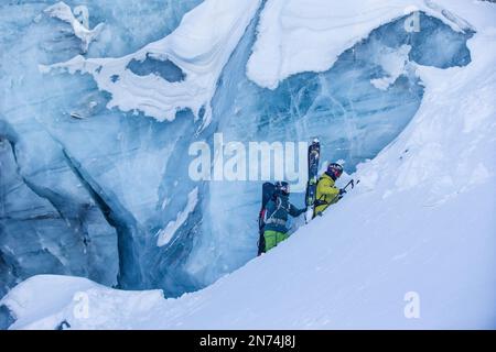 Zwei professionelle Snowboarder und Skifahrer erkunden und fahren eine Gletscherspalte/Eishöhle hoch oben auf dem Pitztal-Gletscher, Pitztal, Tirol, Österreich Stockfoto