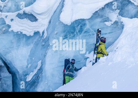 Zwei professionelle Snowboarder und Skifahrer erkunden und fahren eine Gletscherspalte/Eishöhle hoch oben auf dem Pitztal-Gletscher, Pitztal, Tirol, Österreich Stockfoto