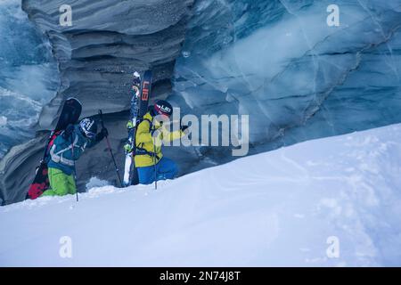 Zwei professionelle Snowboarder und Skifahrer erkunden und fahren eine Gletscherspalte/Eishöhle hoch oben auf dem Pitztal-Gletscher, Pitztal, Tirol, Österreich Stockfoto