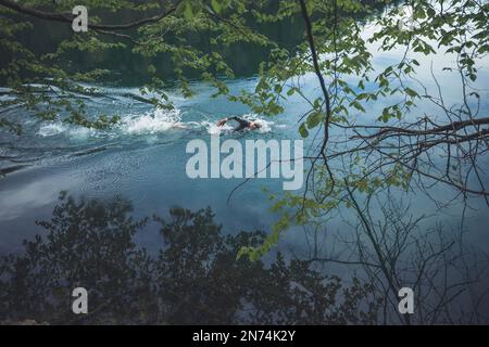 Professioneller Triathlet Schwimmen, Training in einem klaren Bergsee in Allgäu, Alatsee, Bayern, Deutschland Stockfoto