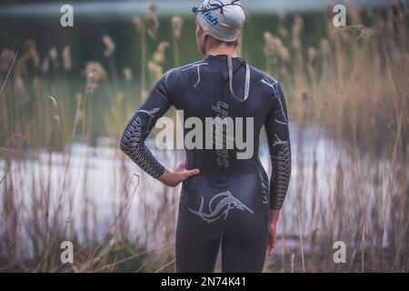 Professioneller Triathlet vor dem Schwimmen, Training in einem klaren Bergsee in Allgäu, Alatsee, Bayern, Deutschland Stockfoto