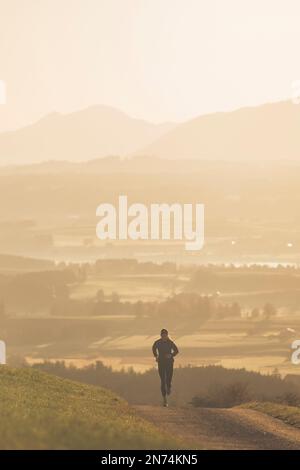 Profitriathleten laufen, Morgenatmosphäre, Sonnenaufgang, Auerberg, Allgäu, Bayern, Deutschland Stockfoto