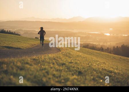 Profitriathleten laufen, Morgenatmosphäre, Sonnenaufgang, Auerberg, Allgäu, Bayern, Deutschland Stockfoto