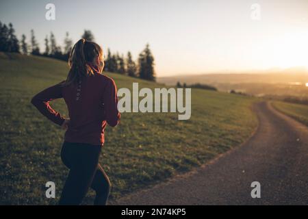 Profitriathleten laufen, Morgenatmosphäre, Sonnenaufgang, Auerberg, Allgäu, Bayern, Deutschland Stockfoto