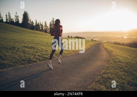 Profitriathleten laufen, Morgenatmosphäre, Sonnenaufgang, Auerberg, Allgäu, Bayern, Deutschland Stockfoto