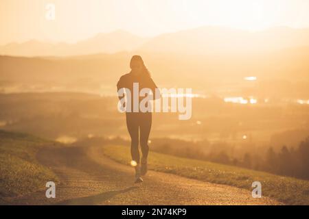 Profitriathleten laufen, Morgenatmosphäre, Sonnenaufgang, Auerberg, Allgäu, Bayern, Deutschland Stockfoto