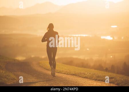 Profitriathleten laufen, Morgenatmosphäre, Sonnenaufgang, Auerberg, Allgäu, Bayern, Deutschland Stockfoto